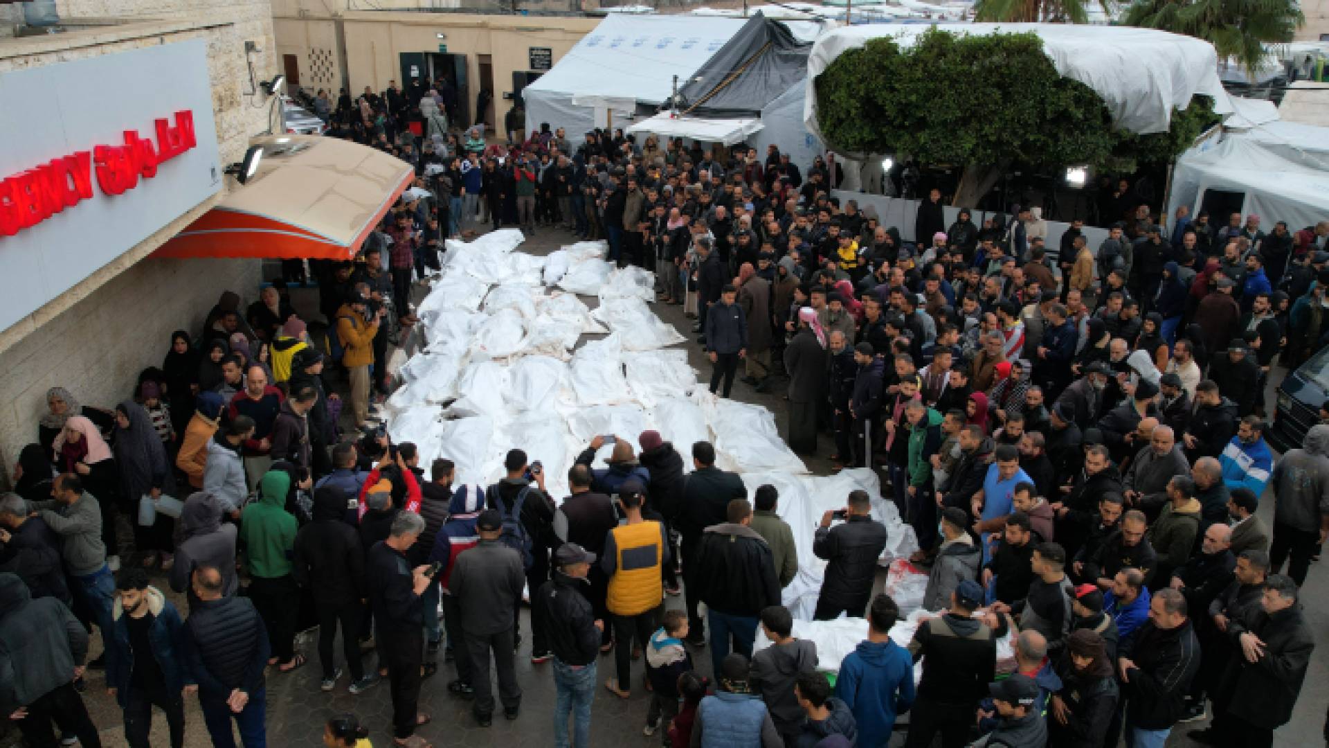 فلسطينيون يتحضرون لتشييع جثامين من ارتقوا بقصف للاحتلال استهدف مخيم المغازي في قطاع غزة ليلة عيد الميلاد