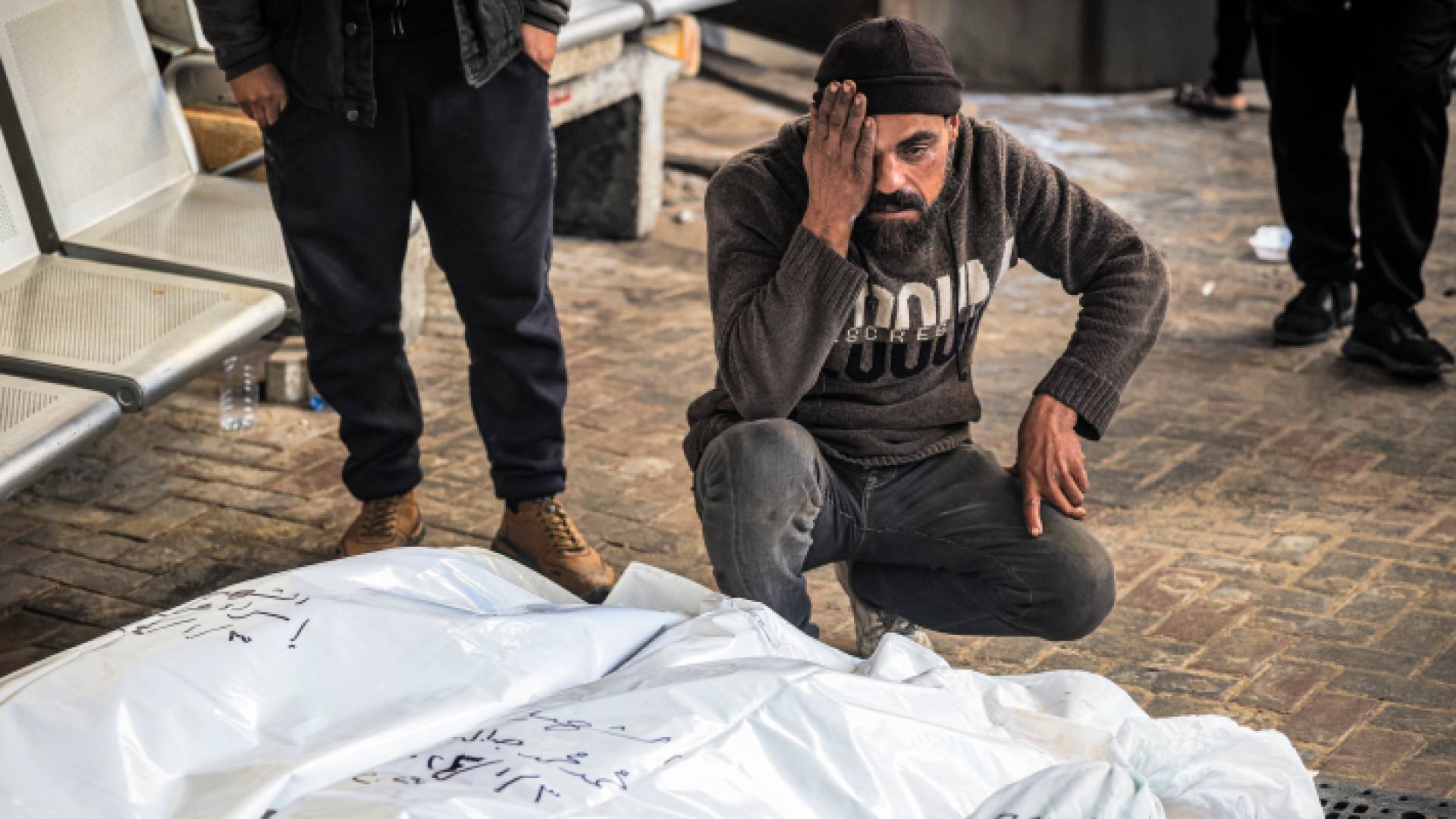 فلسطيني يجلس بجانب جثمان أحد أقاربه الذي ارتقى في قطاع غزة