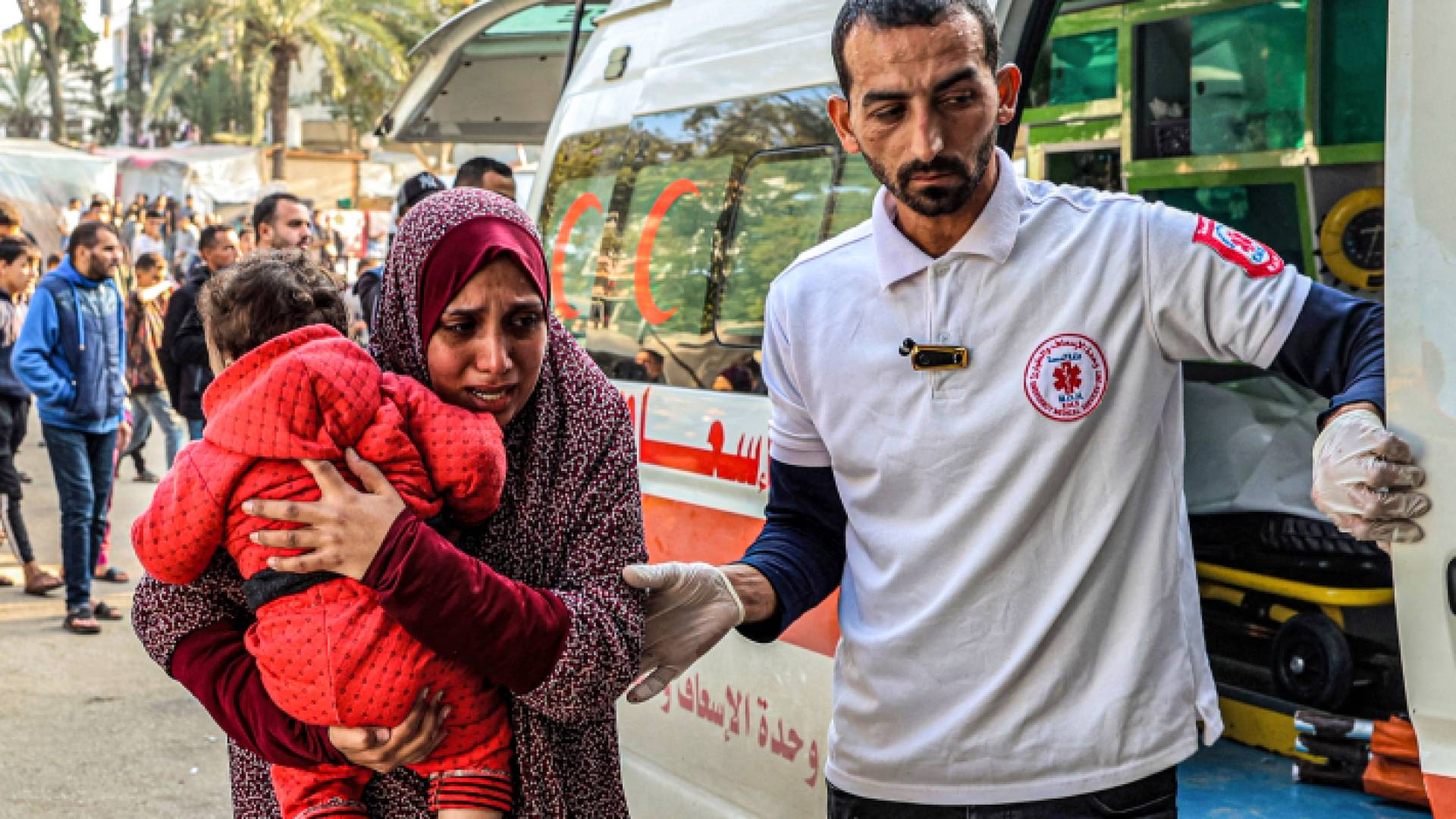 فلسطينية تحمل طفل مصاب جراء قصف الاحتلال على قطاع غزة