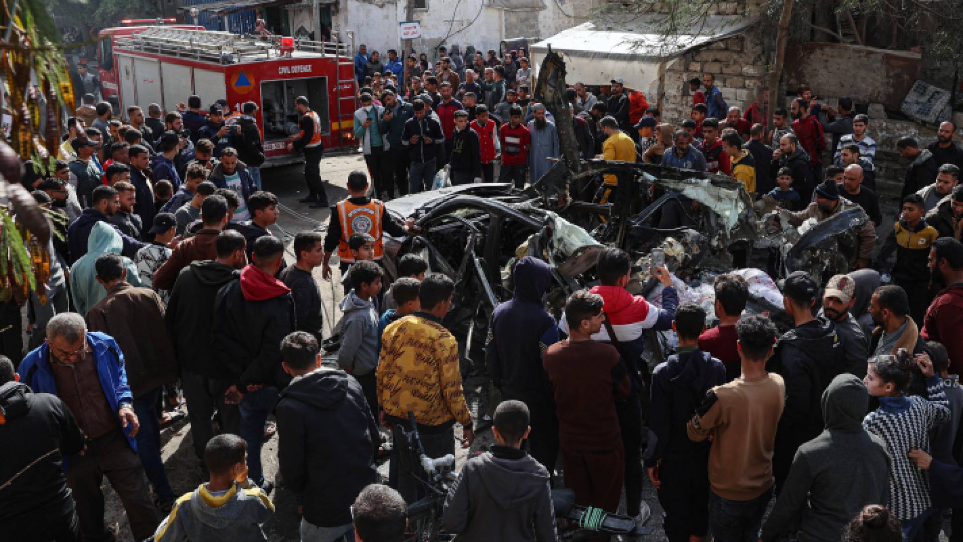 فلسطينيون يقفون عند مركبة استهدفتها قوات الاحتلال في قطاع غزة