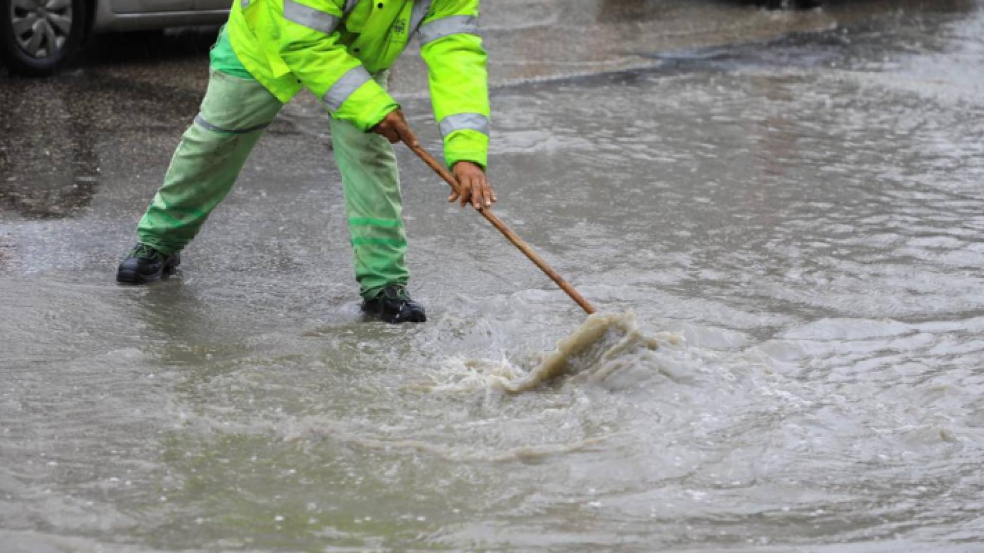 عامل وطن يحاول فتح أحد المزاريب لتسليك مياه الأمطار