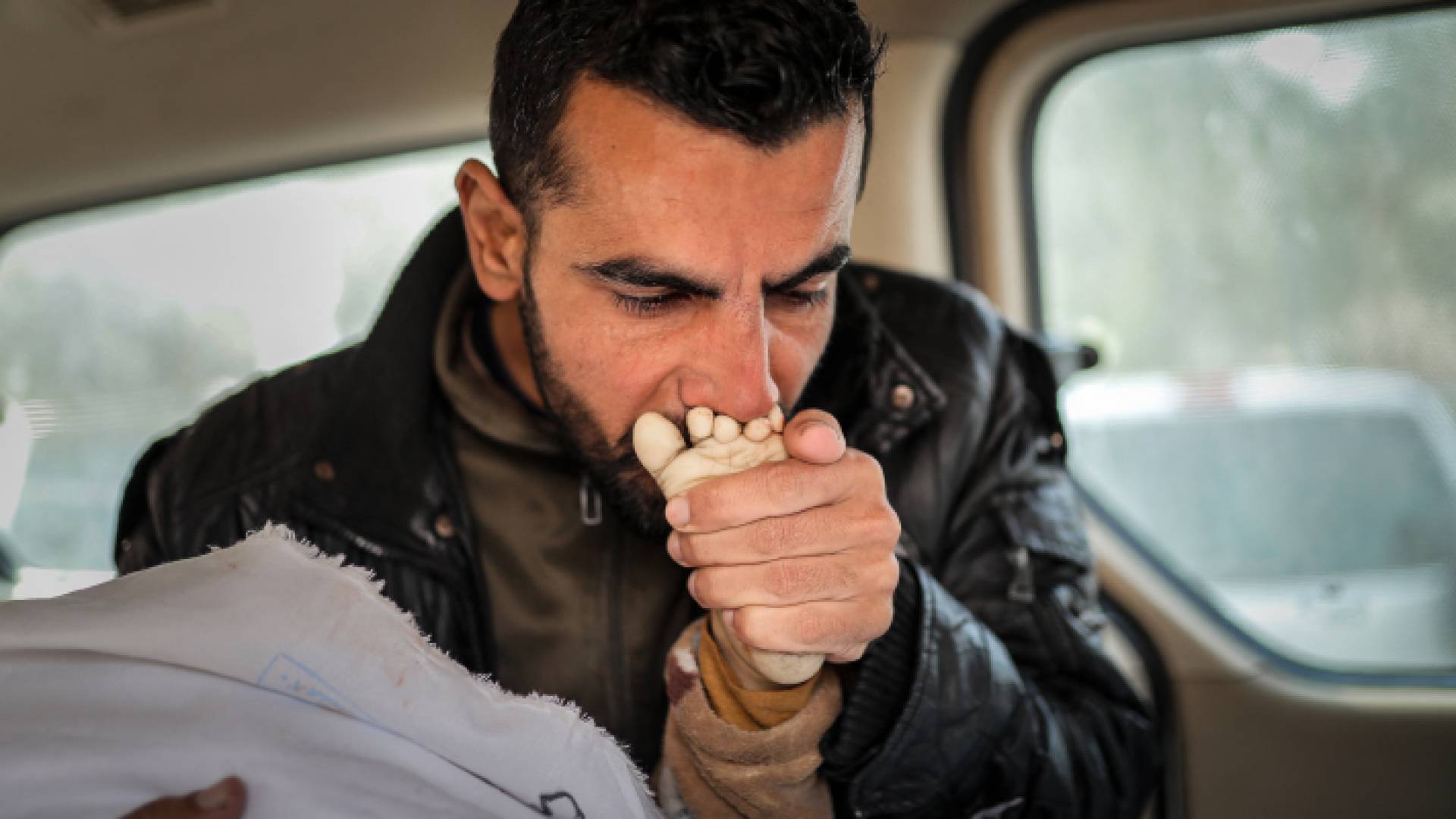 فلسطيني يقبل قدم طفل شهيد في غزة - AFP