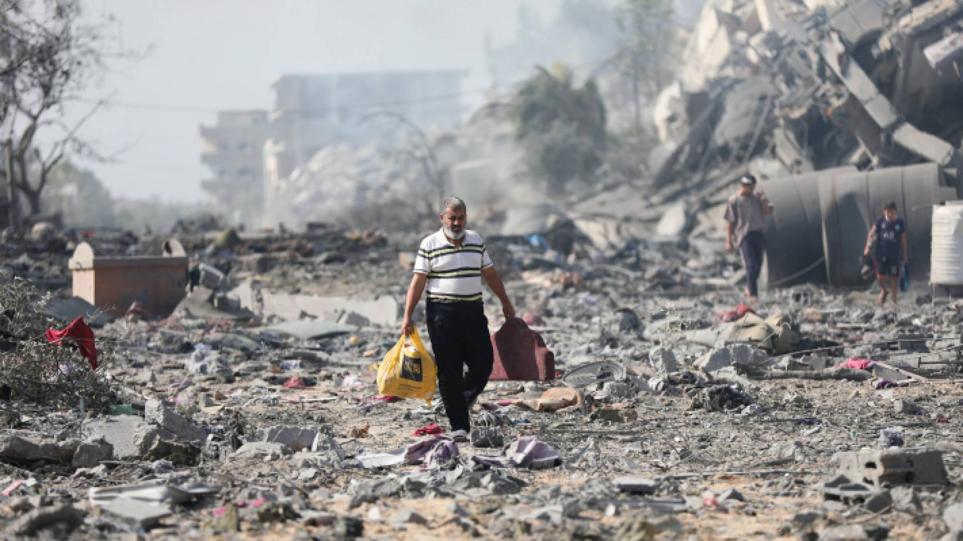 فلسطينيون يسيرون بين المباني المدمرة في قطاع غزة