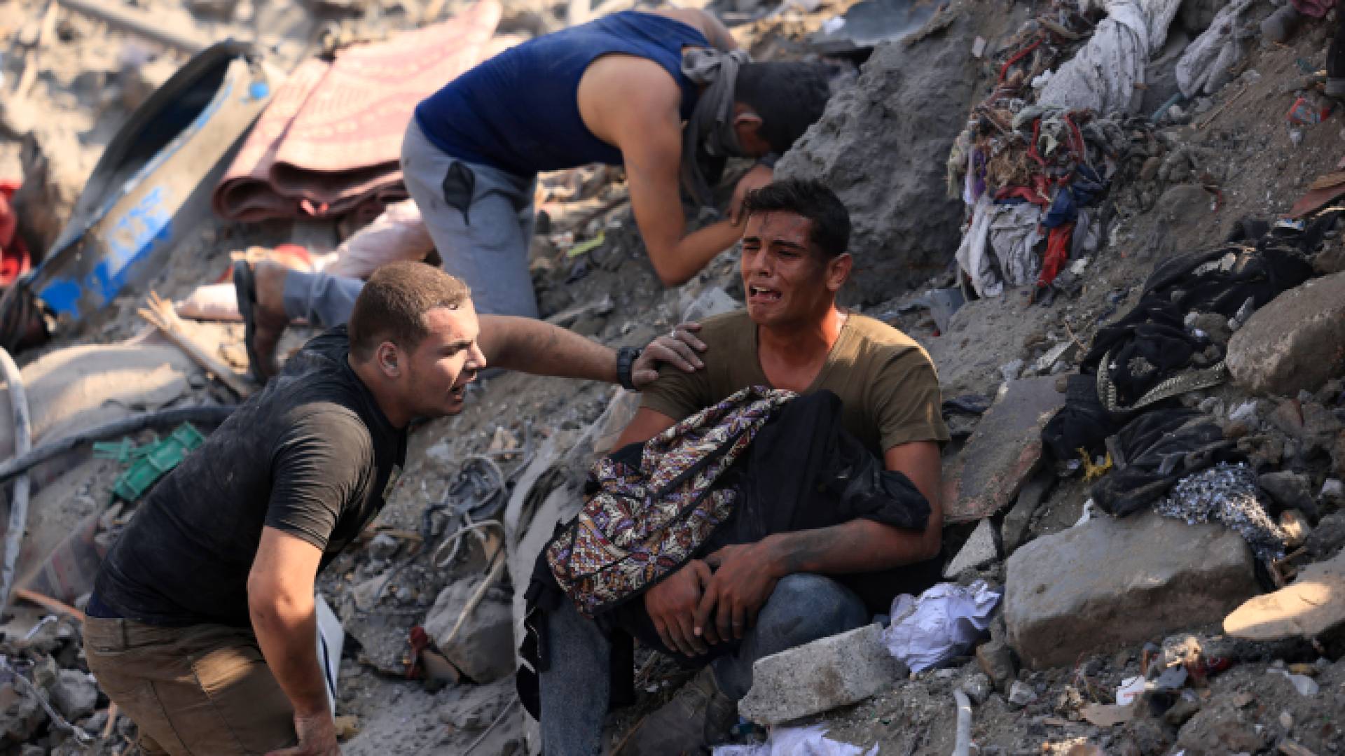 فلسطينيون يجلسون على أنقاض أحد المنازل الذي دمرته غارات للاحتلال الإسرائيلي في قطاع غزة