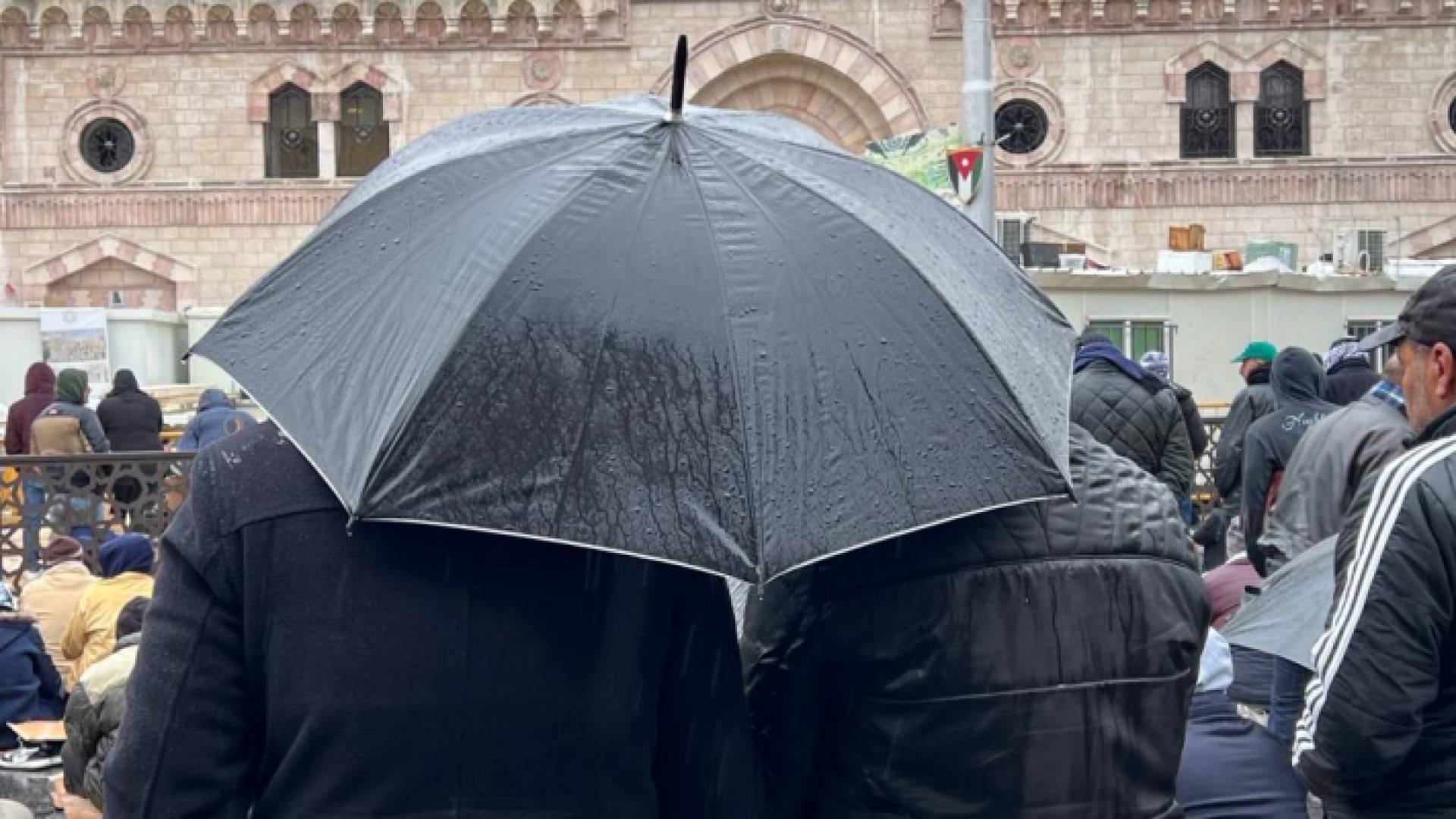 شخصان يحملان مظلة وسط أجواء ماطرة في العاصمة عمان