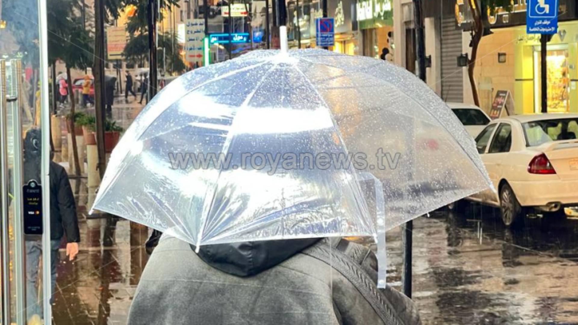 شخص يحمل مظلة وسط زخات المطر في عمان