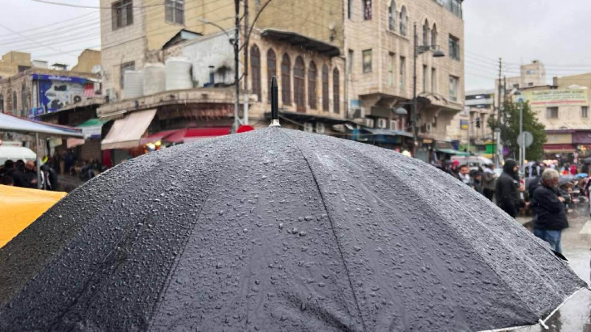 شخص يحمل مظلة في أحد شورع العاصمة عمان