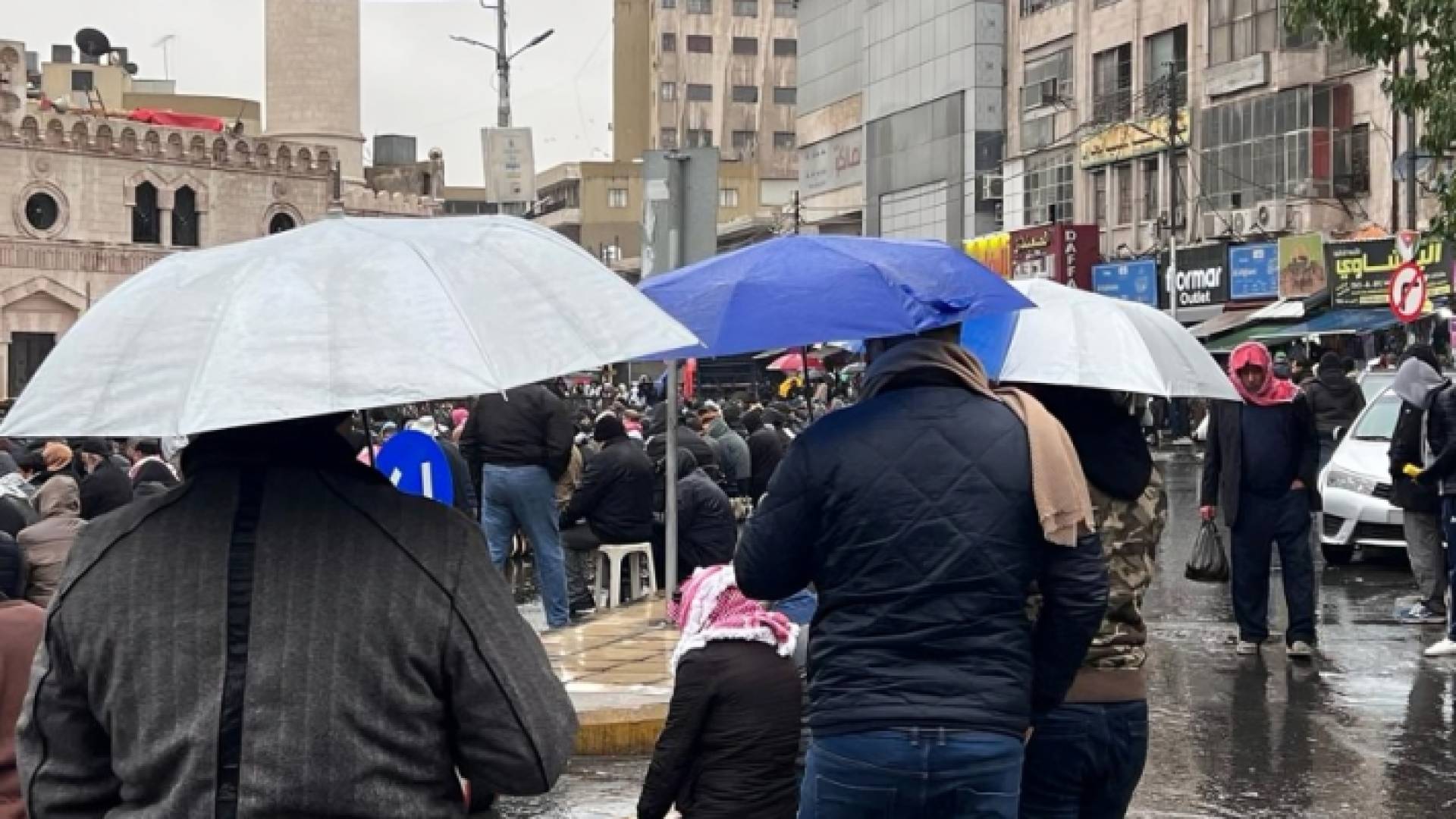 أردنيون يحملون مظلات خلال هطول الأمطار