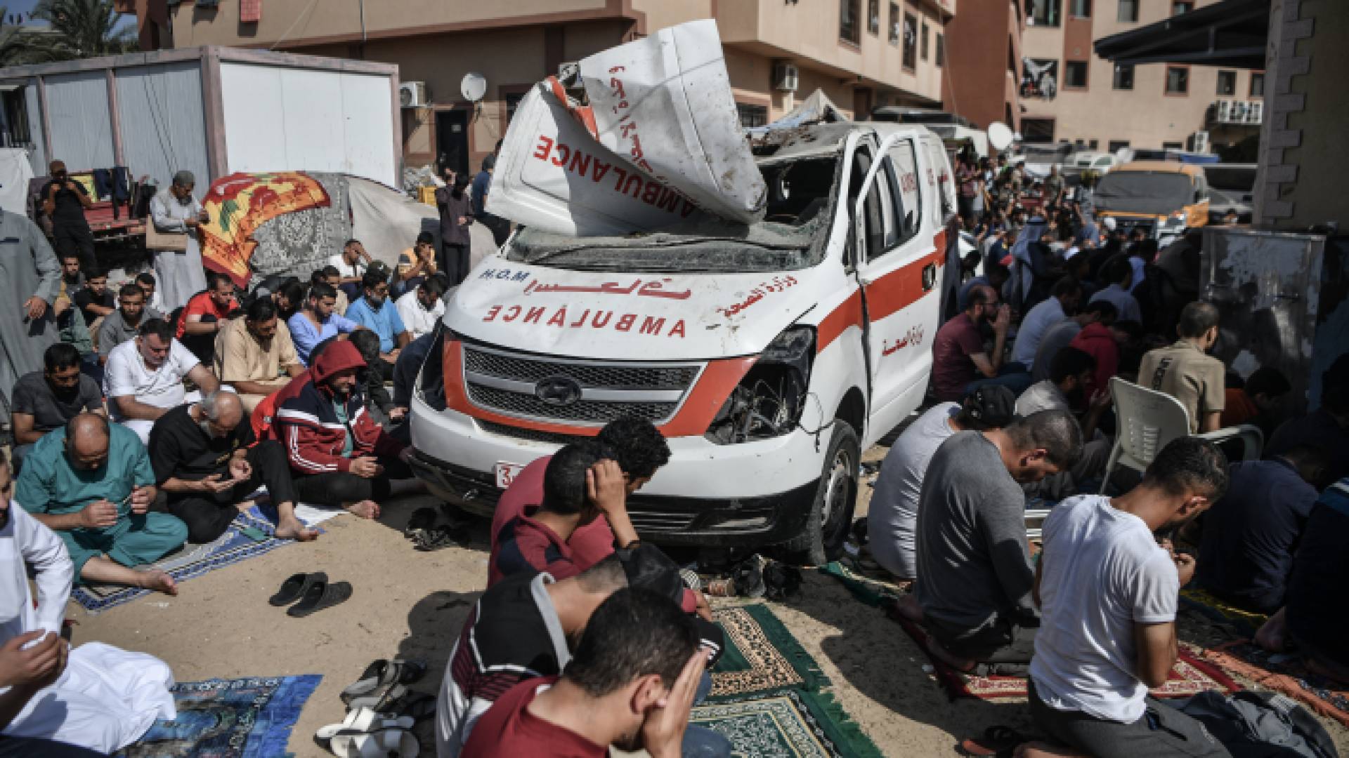 غزيون يصلون بالقرب من سيارة إسعاف مدمرة إثر قصف الاحتلال