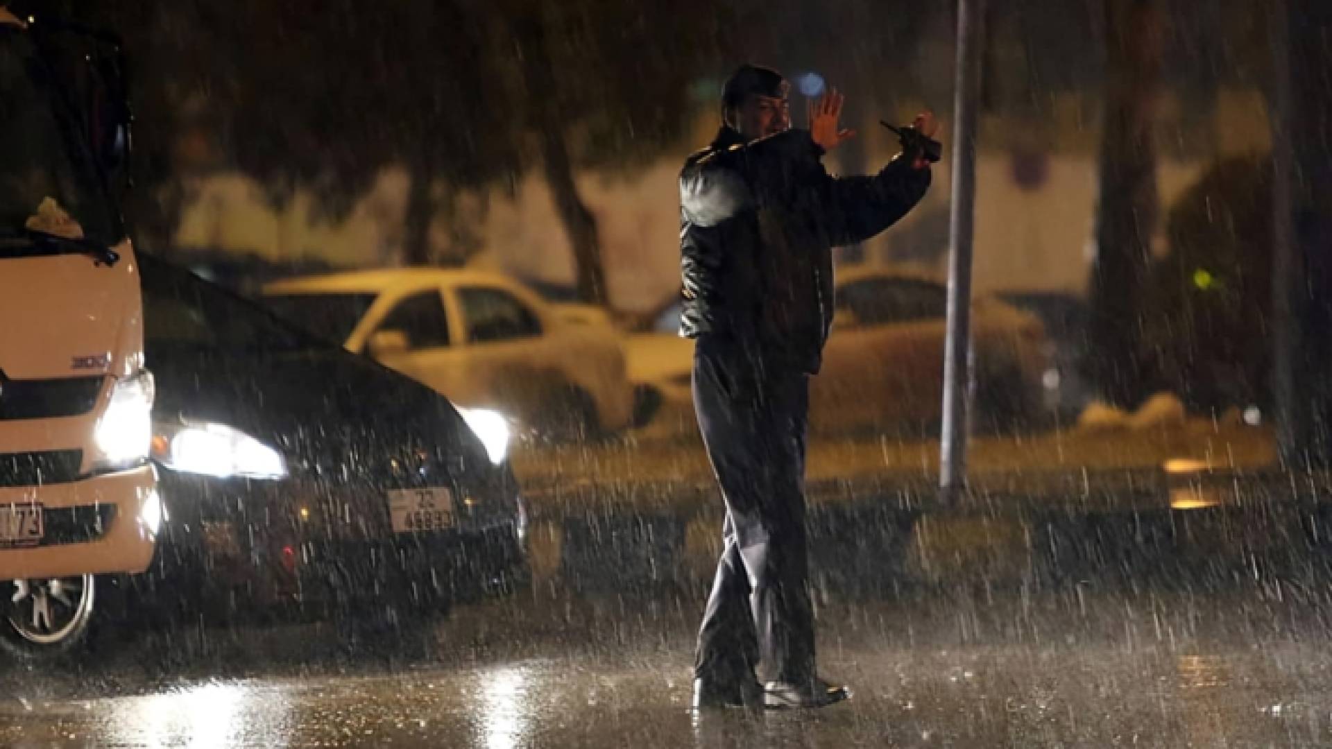 رجل أمن ينظم السير تحت الأمطار الغزيرة