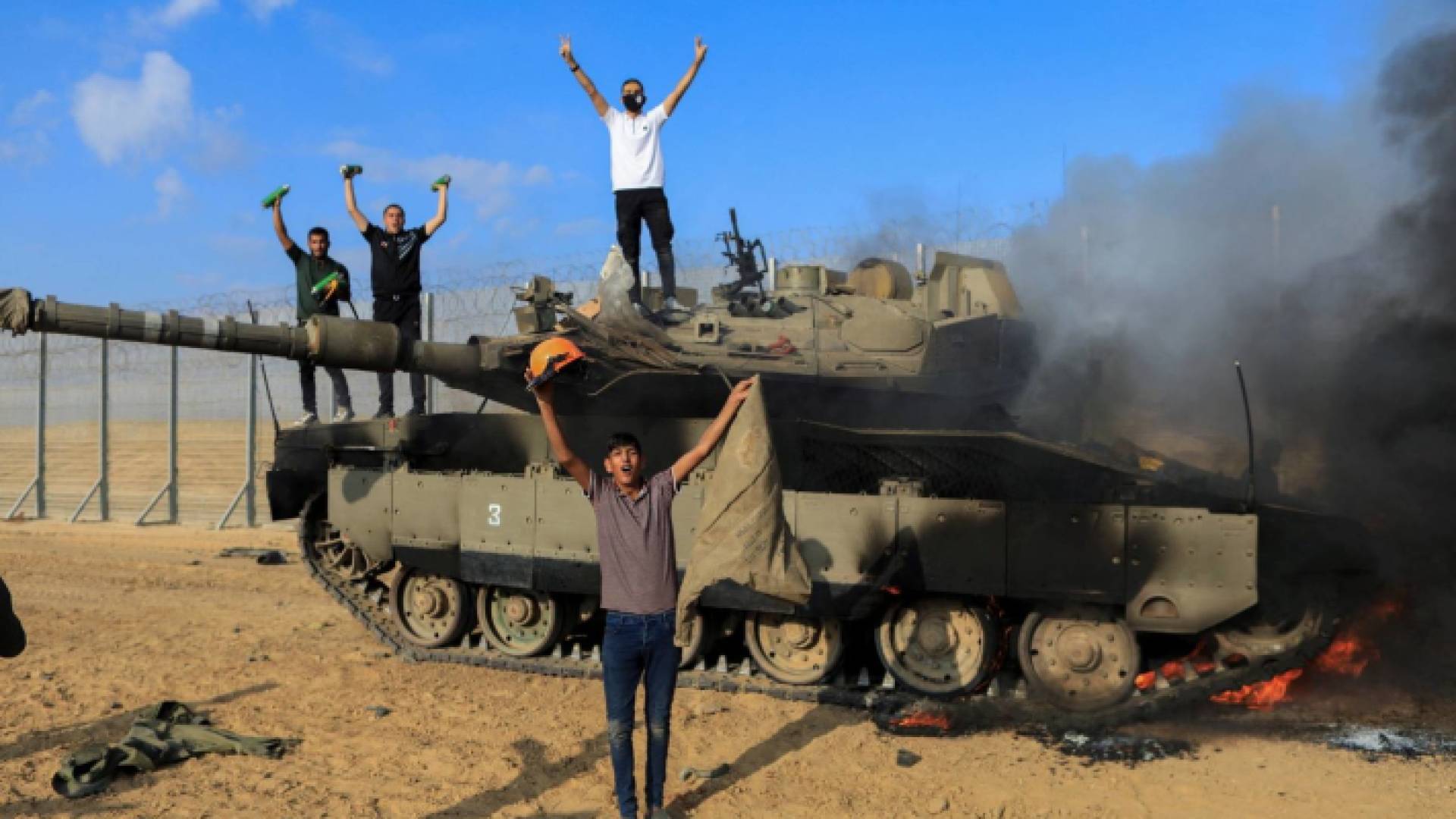 فلسطينيون يصعدون فوق دبابة مدمرة في السابع من أكتوبر