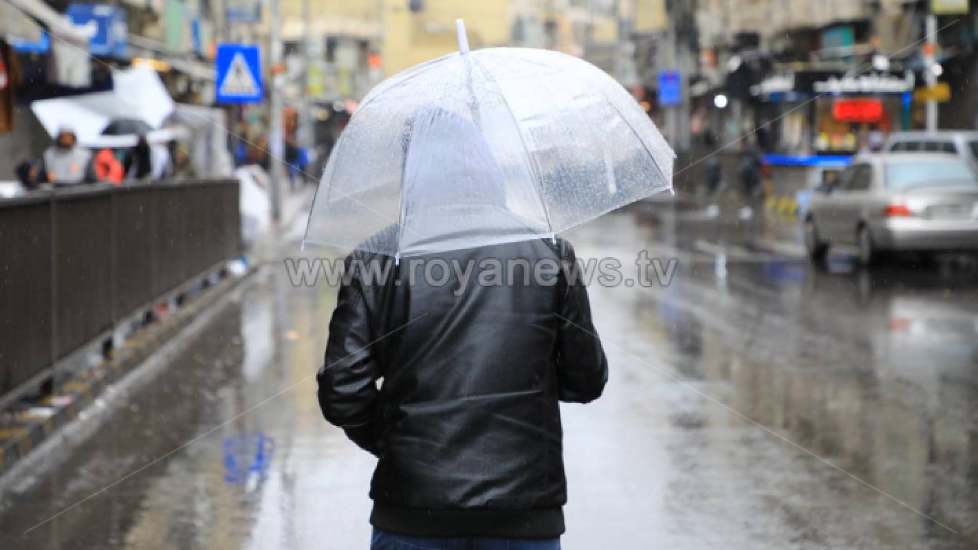 شخص يسير تحت المطر في وسط البلد بعمان