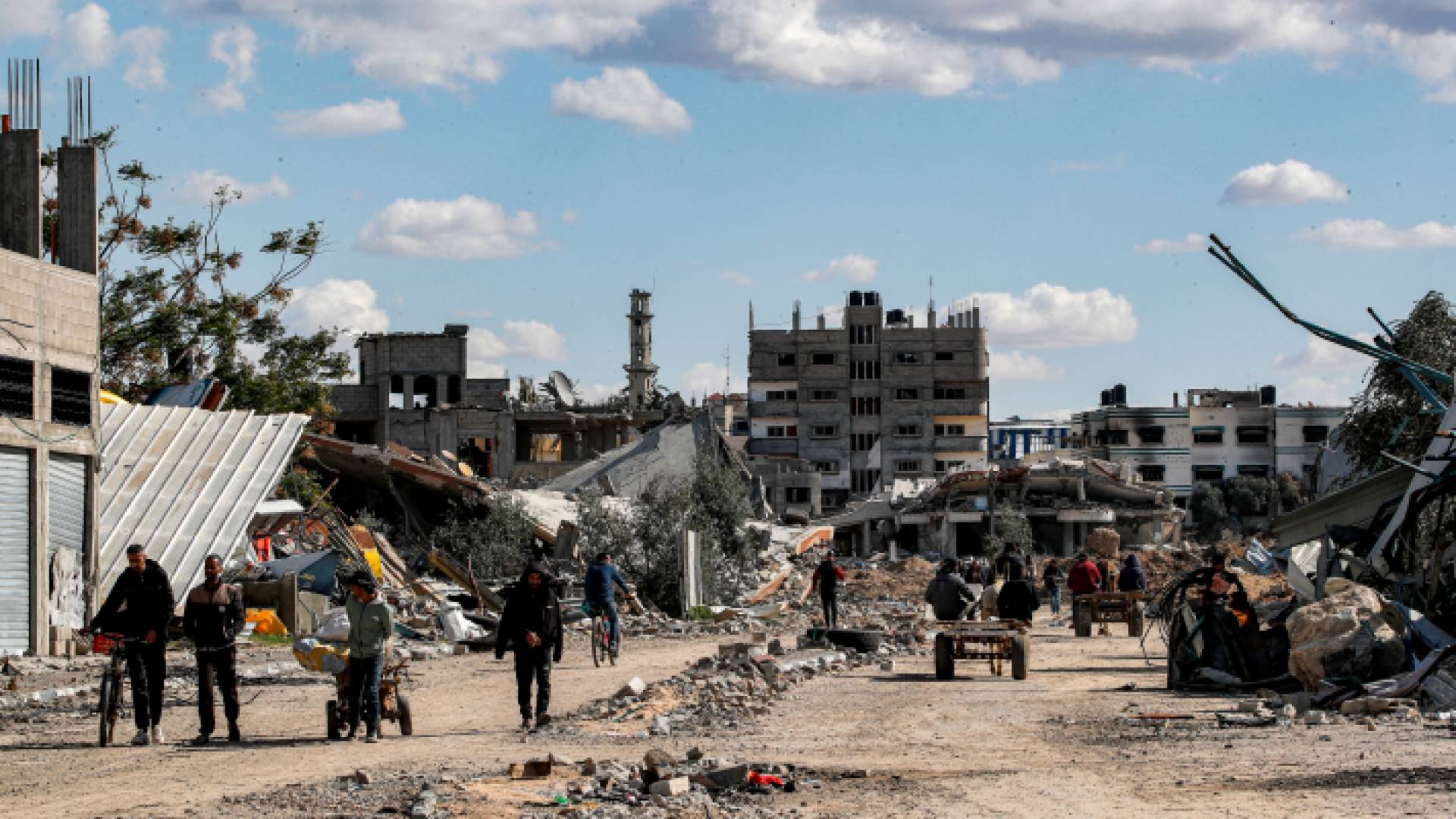 فلسطينيون وسط المباني المدمرة في مخيم المغازي للاجئين الفلسطينيين