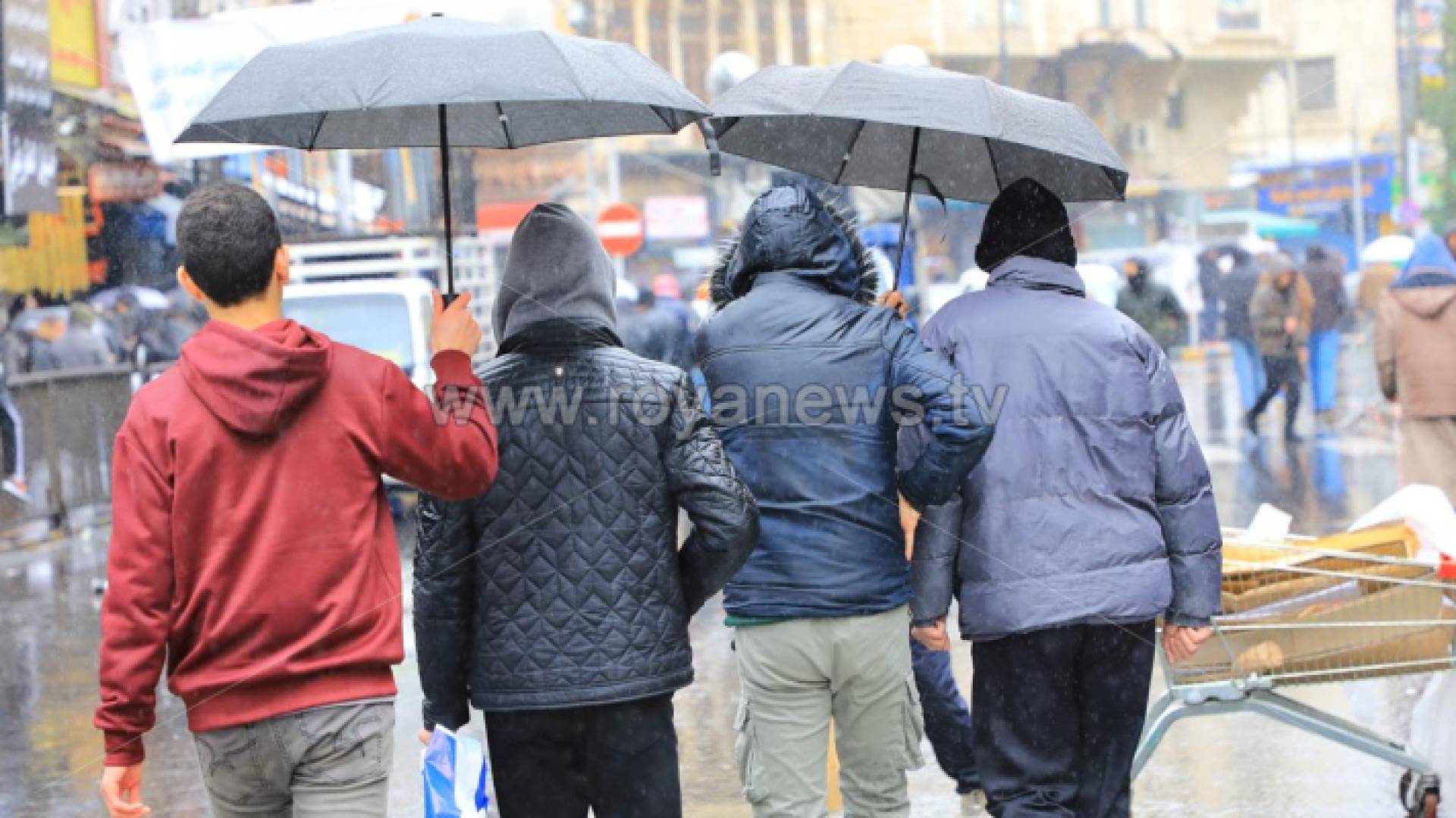 أشخاص يسيرون وسط أجواء ماطرة وسط العاصمة عمان