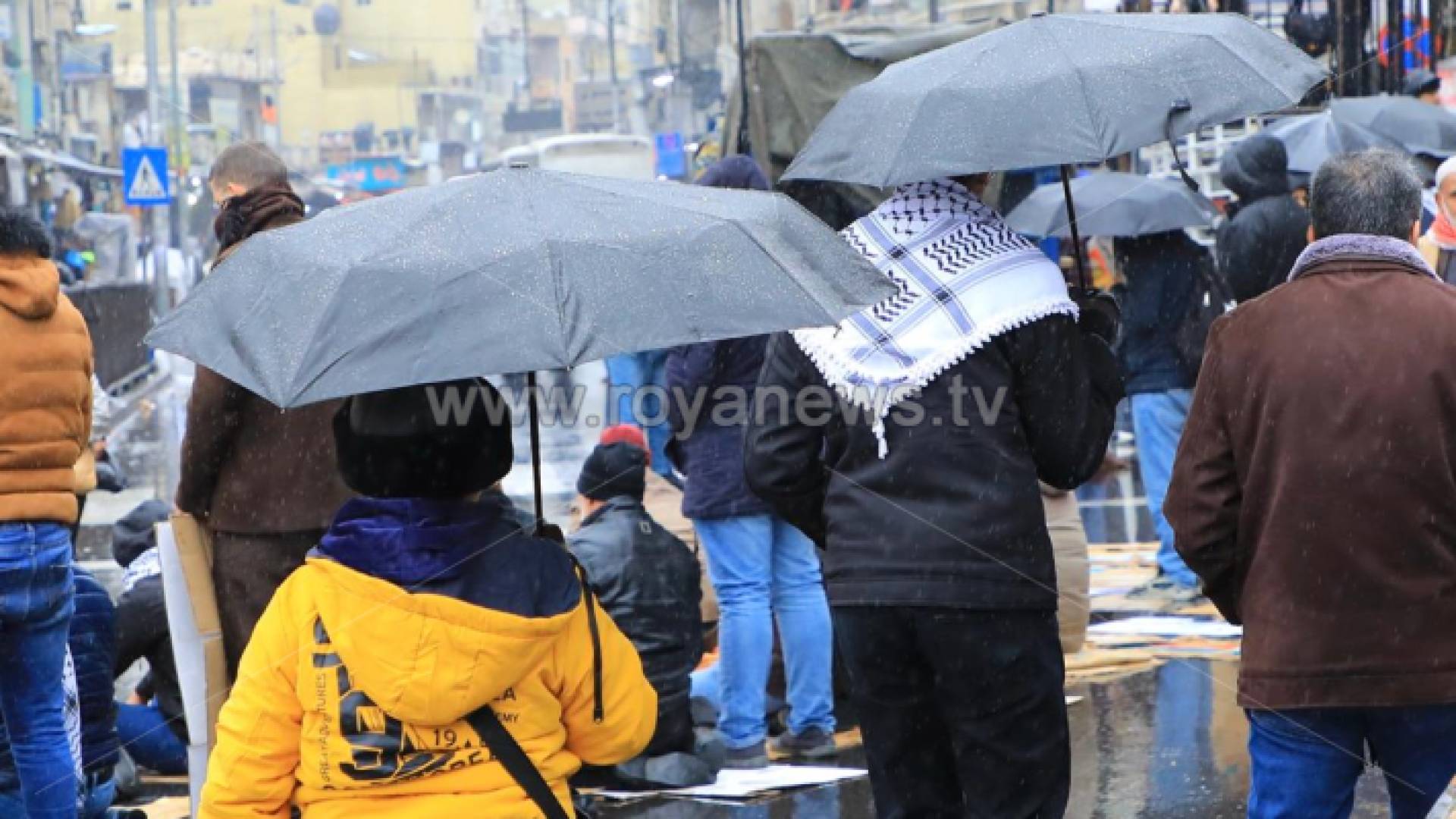 أشخاص يحملون مظلات في الأجواء الماطرة بالأردن