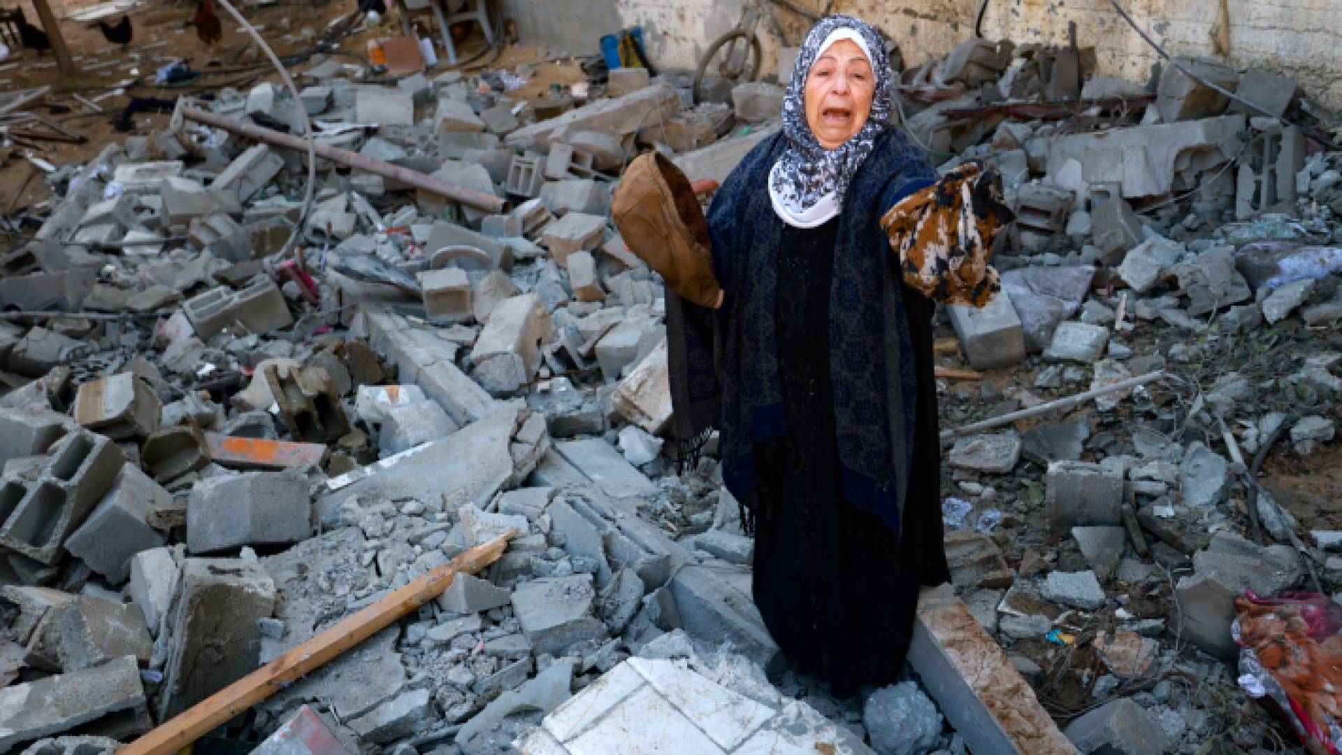 سيدة فلسطينية تقف عند ركام منزلها في قطاع غزة