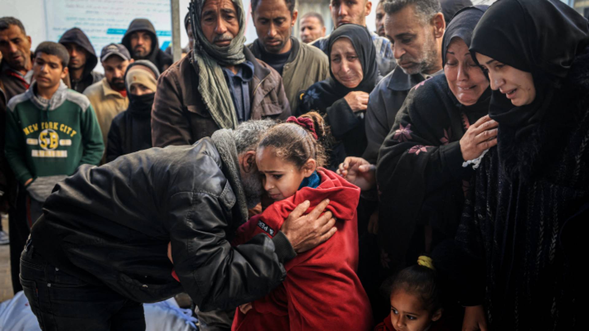 فلسطينيون يبكون عند جثامين شهداء أقارب لهم ارتقوا خلال عدوان الاحتلال على قطاع غزة