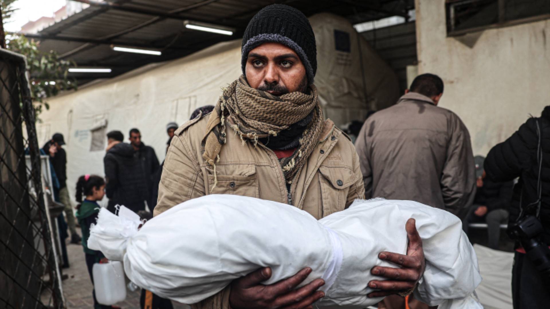 فلسطيني يحمل صغيره الشهيد في غزة