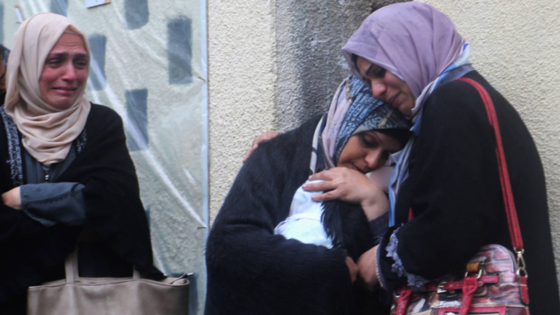 فلسطينية تحمل صغيرها الشهيد في غزة