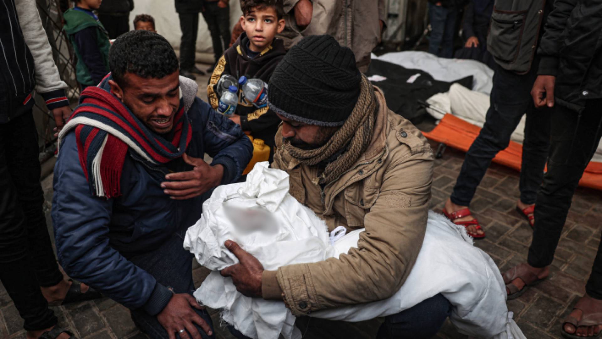 فلسطيني يحمل صغيره الشهيد في غزة