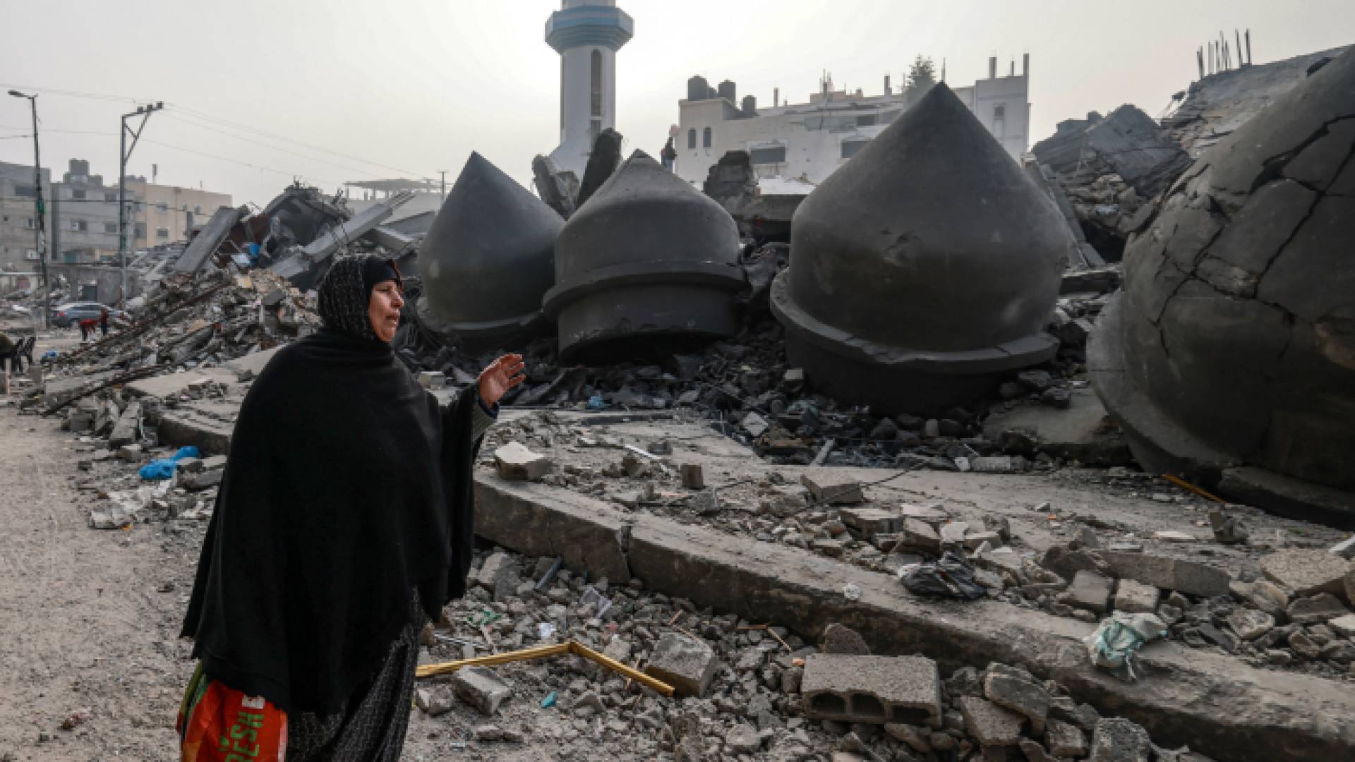 مسنة فلسطينية تسير بالقرب من مسجد الفاروق الذي دمره قصف الاحتلال في رفح - AFP