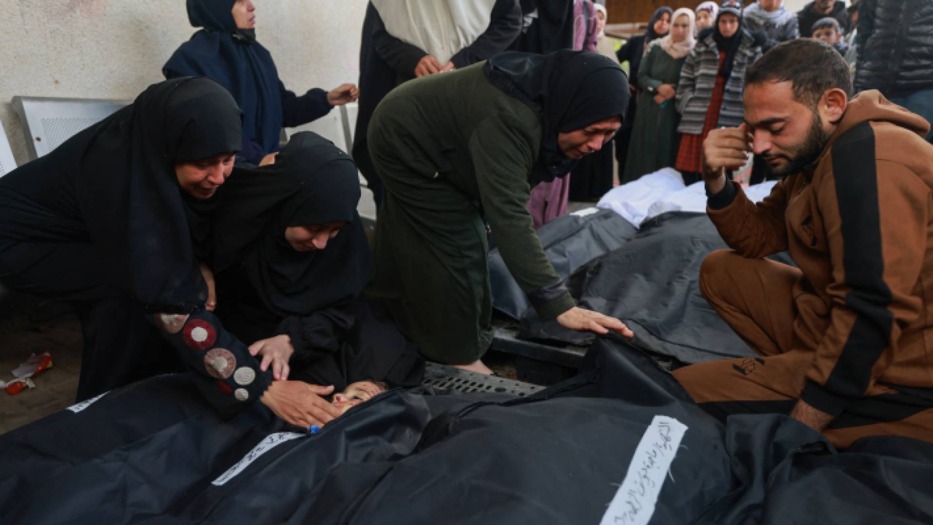 فلسطينيون بالقرب من شهداء جراء عدوان الاحتلال في مخيم رفح - AFP