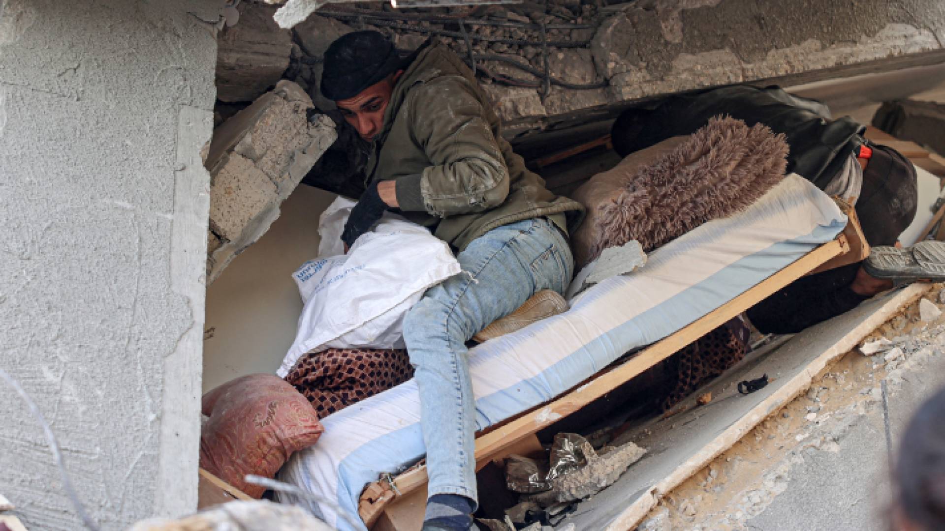 فلسطينيان محاصران تحت سقف أحد المنازل المدمرة في غزة