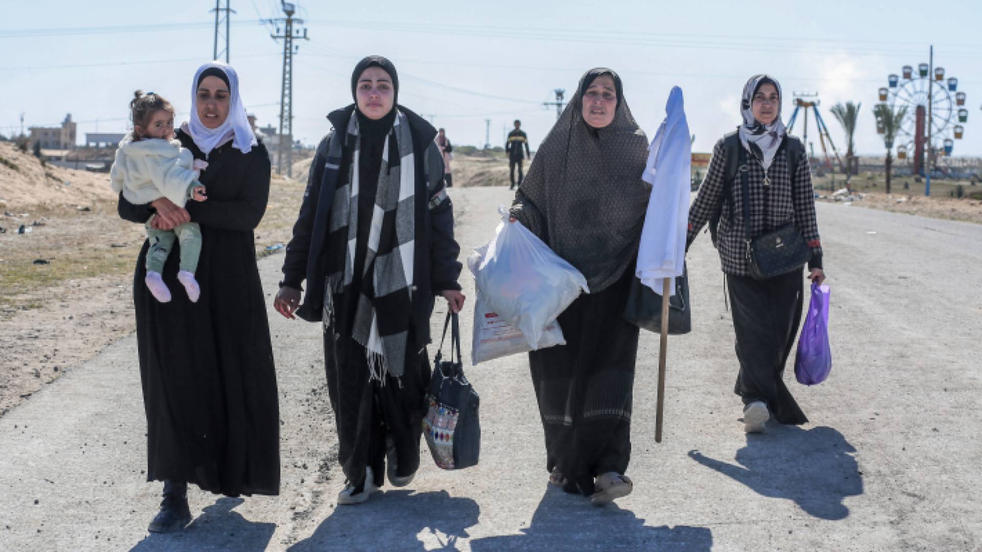 فلسطينيات نازحات يحملن أمتعتهن ورايات بيضاء أثناء سيرهن أمام قوات الاحتلال في خان يونس جنوبي قطاع غزة