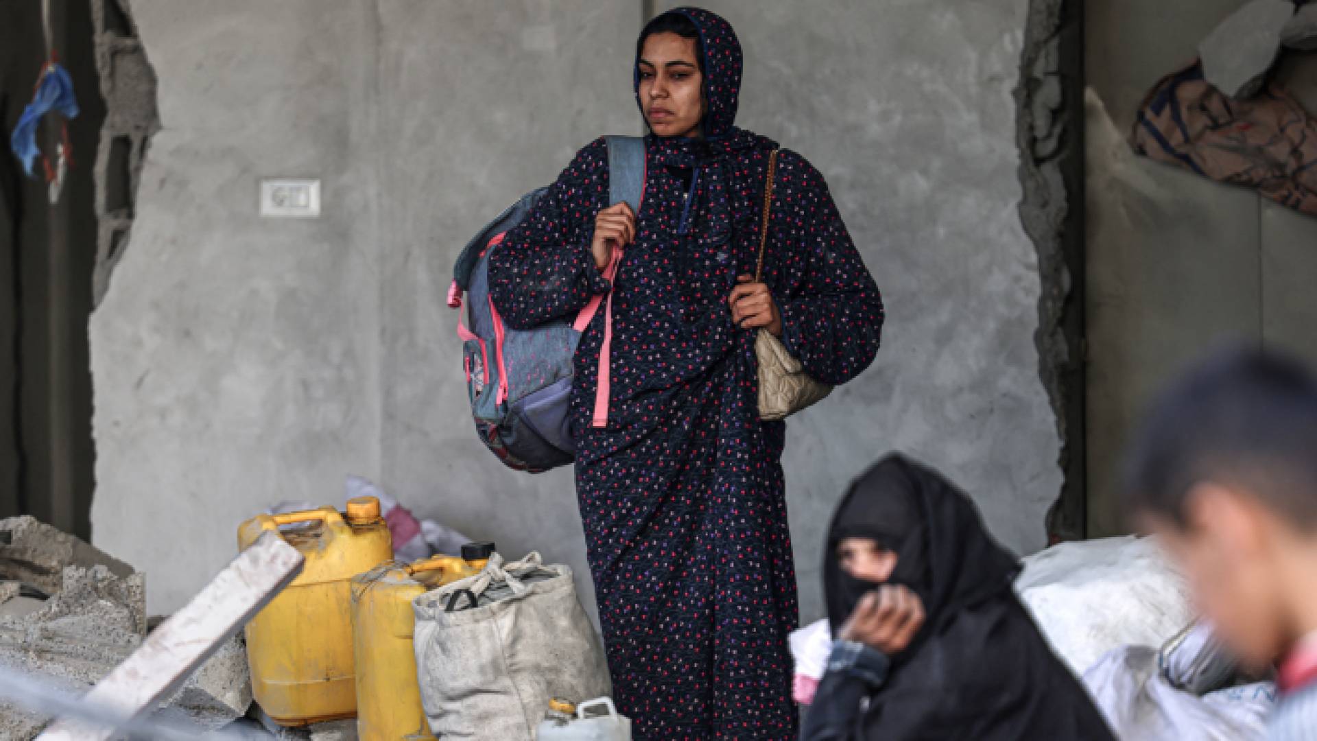 فلسطينية تحمل بعضا من الممتلكات التي تم انتشالها من تحت أنقاض شقتها في مبنى سكني أصيب بغارة للاحتلال في رفح جنوبي قطاع غزة