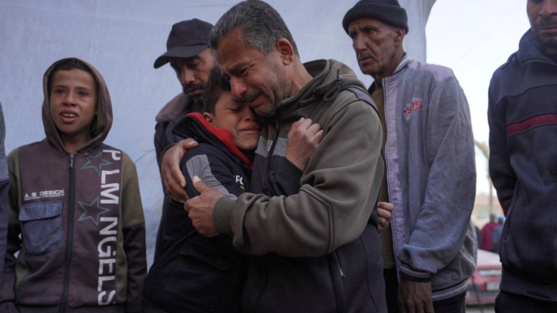 فلسطيني يحتضن ابنه بعد استشهاد أفراد من عائلتهم في دير البلح وسط قطاع غزة