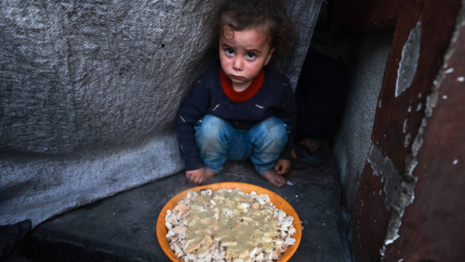 طفل فلسطيني يجلس بجوار طبق قبل تناول وجبة "الإفطار" في شهر رمضان - AFP