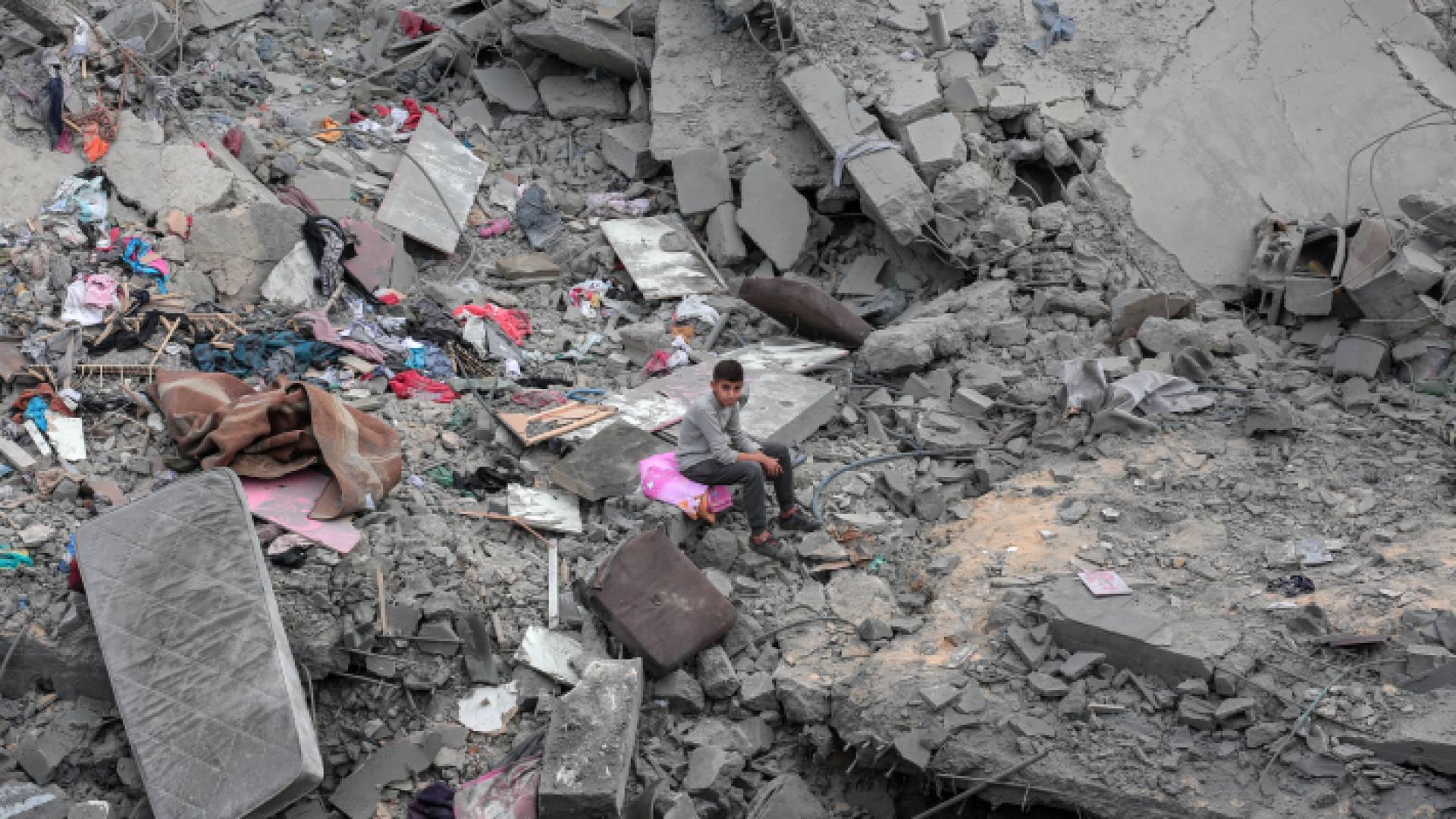 صبي يجلس بين الأنقاض بعد تدمير منزل في غارة للاحتلال - AFP