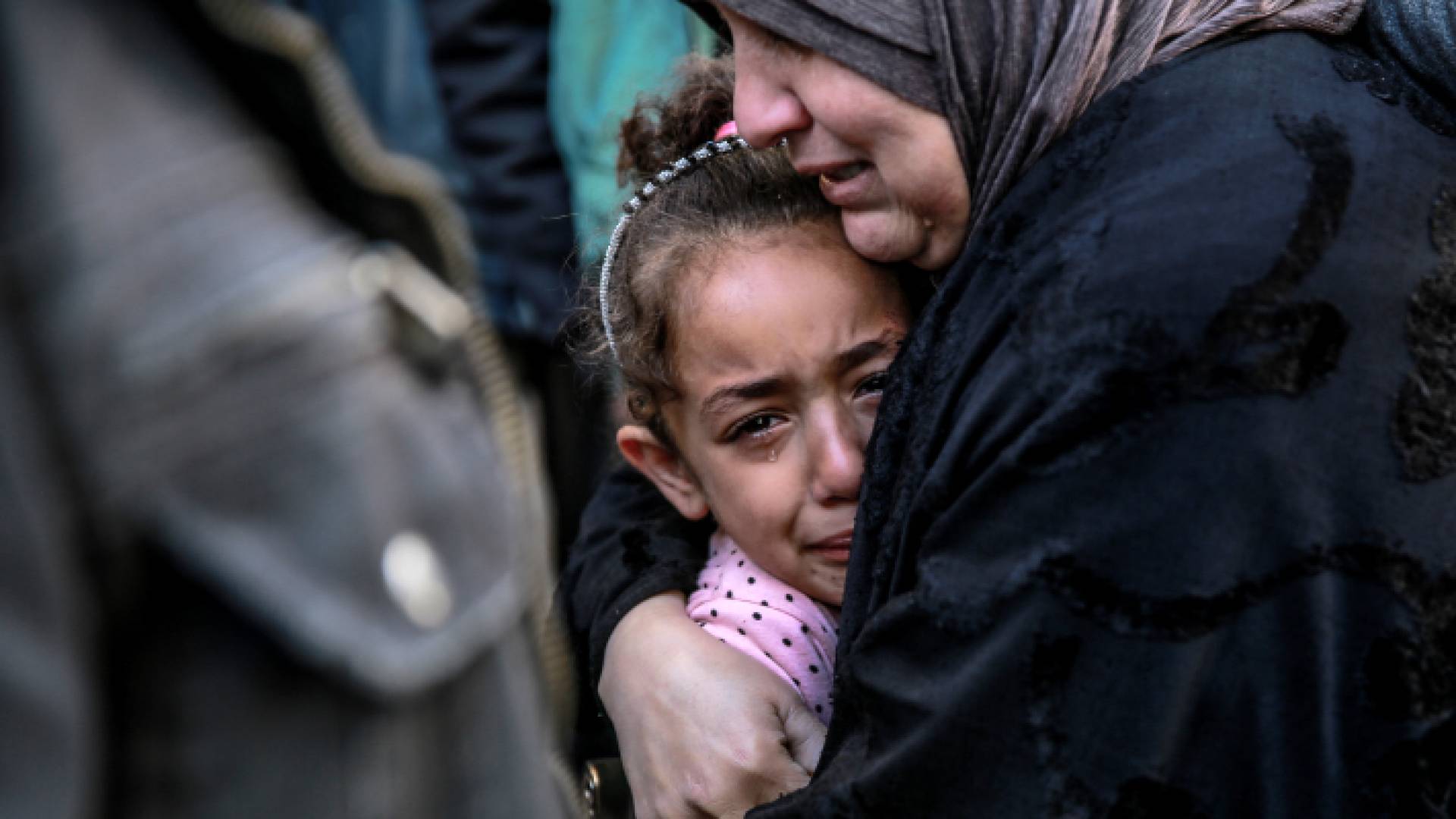 أم فلسطينية تحتضن صغيرتها التي تبكي حزنا وقهرا في غزة