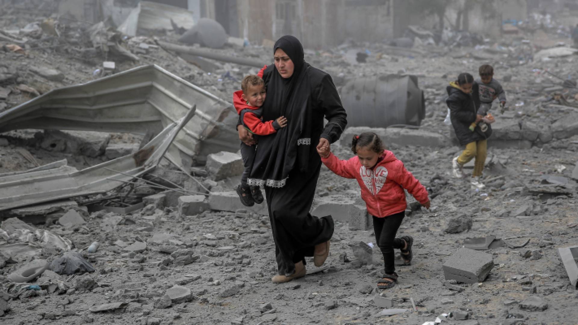 فلسطينية تحاول الوصول بأطفالها إلى مكان آمن في غزة