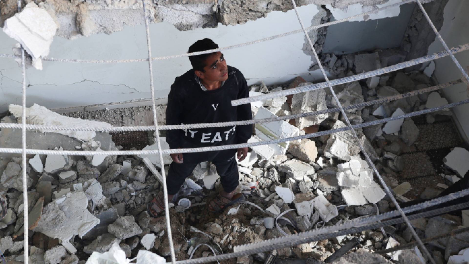 فلسطيني ينظر للدمار الذي لحق منزل عائلته جراء العدوان