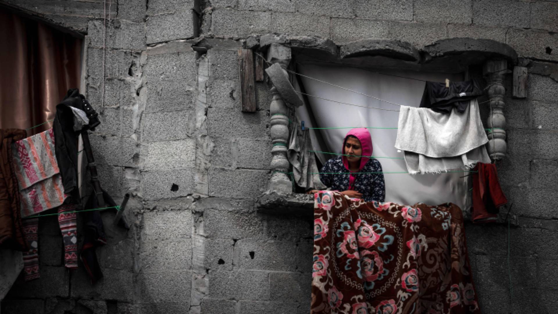 فلسطينية تقف على نافذة مبنى تضرر من قصف الاحتلال في رفح جنوبي القطاع - AFP