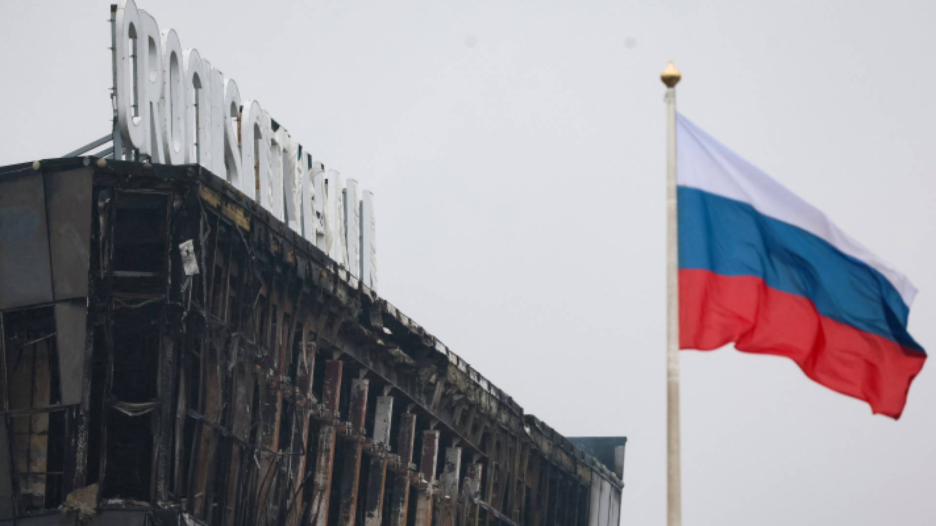 العلم الروسي في مهب الريح قرب قاعة الحفلات الموسيقية المحترقة مسرح الهجوم المسلح