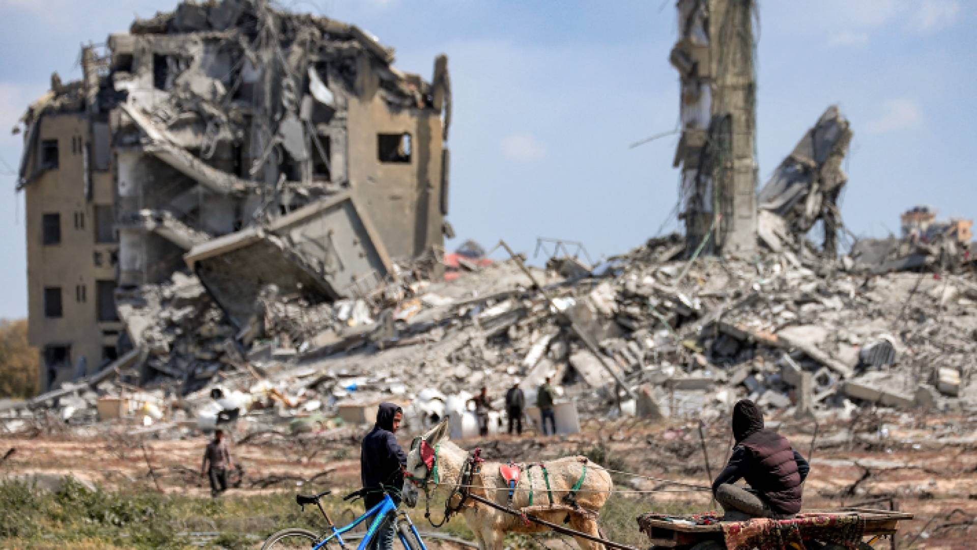 شخص يراقب الناس وهم يبحثون في أنقاض المباني المدمرة في شمالي غزة - AFP