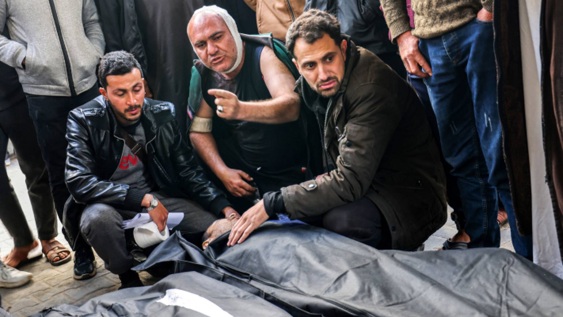 فلسطينيون يجلسون بالقرب من شهدائهم