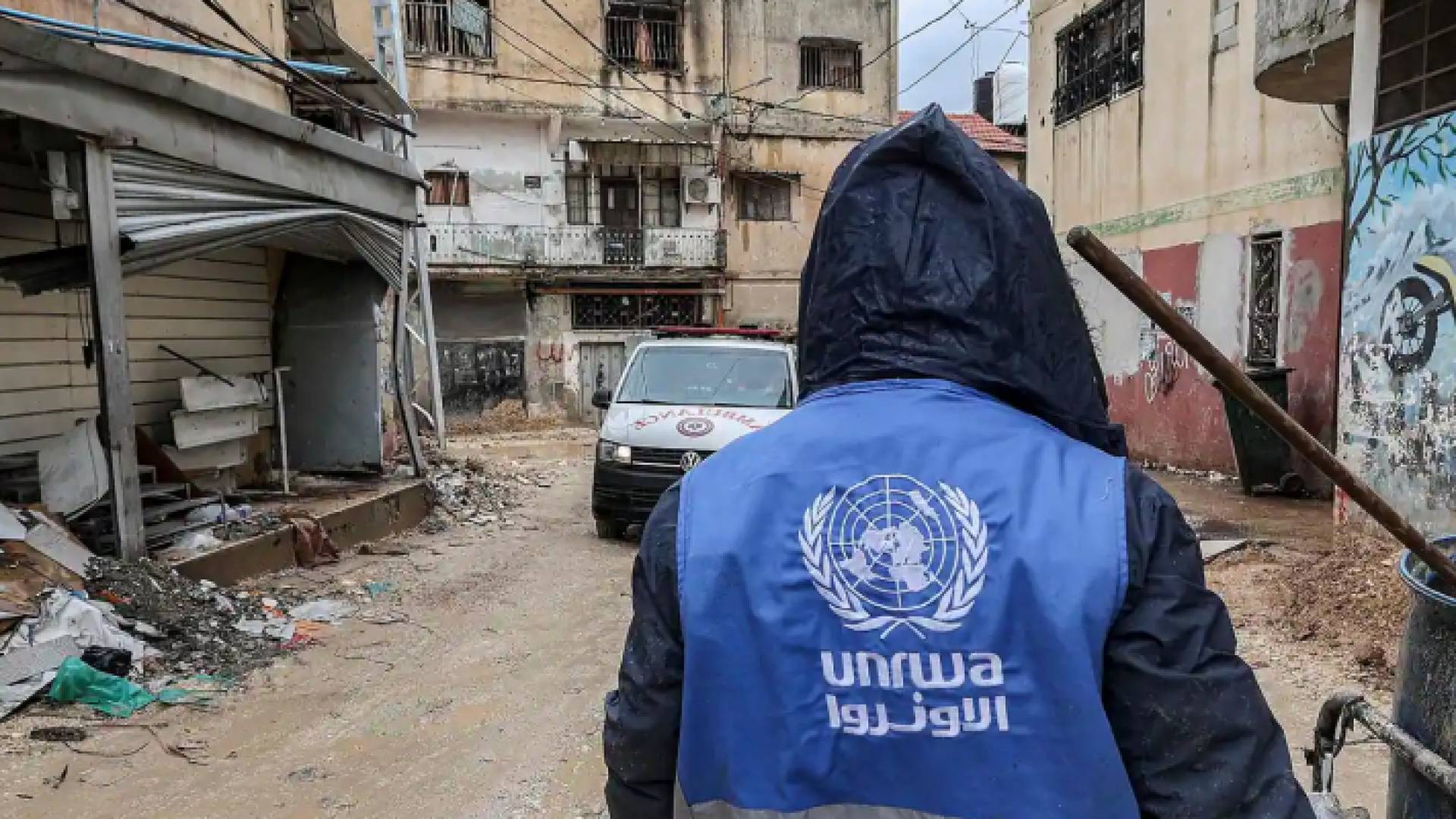شخص يرتدي سترة تحمل شعار وكالة "الأونروا"