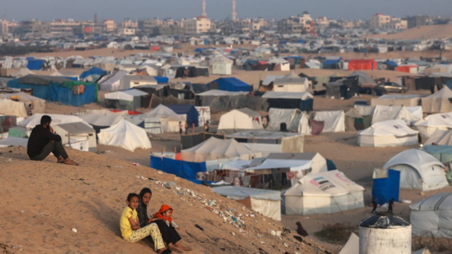 أطفال فلسطينيون يجلسون على تلة بجوار خيام تأوي النازحين في رفح جنوبي قطاع غزة