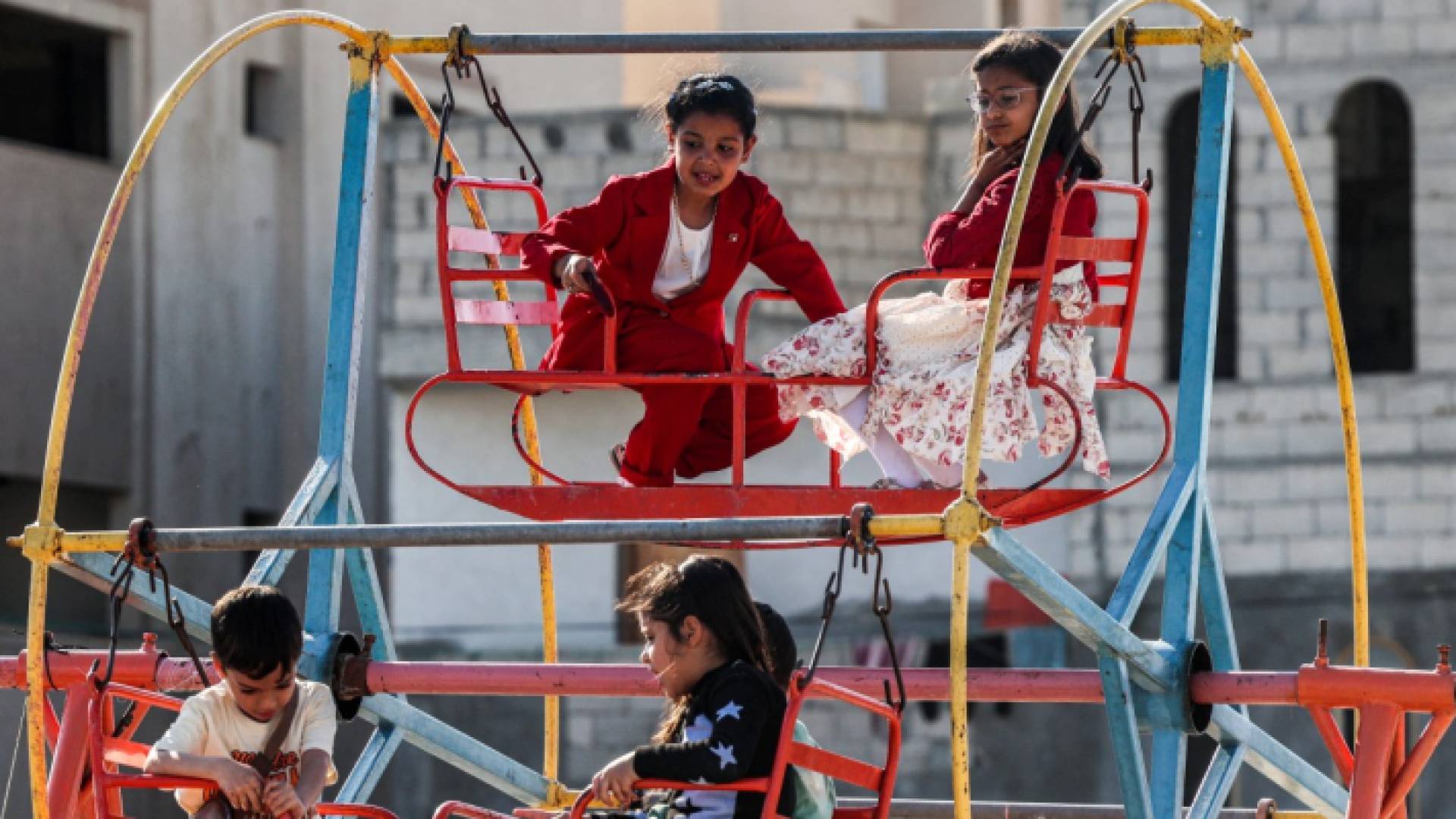 أطفال يجلسون على أرجوحة وهم يحتفلون في اليوم الأول من عيد الفطر - AFP