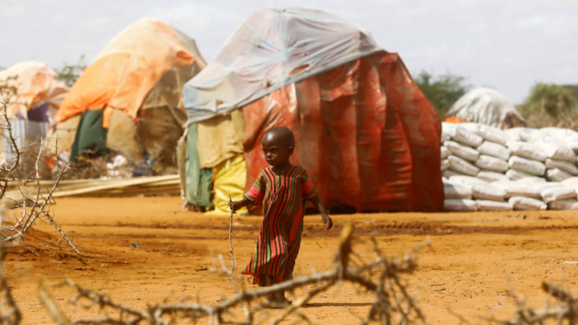 طفل بالقرب من خيام لاجئين يعانون من نقص الغذاء