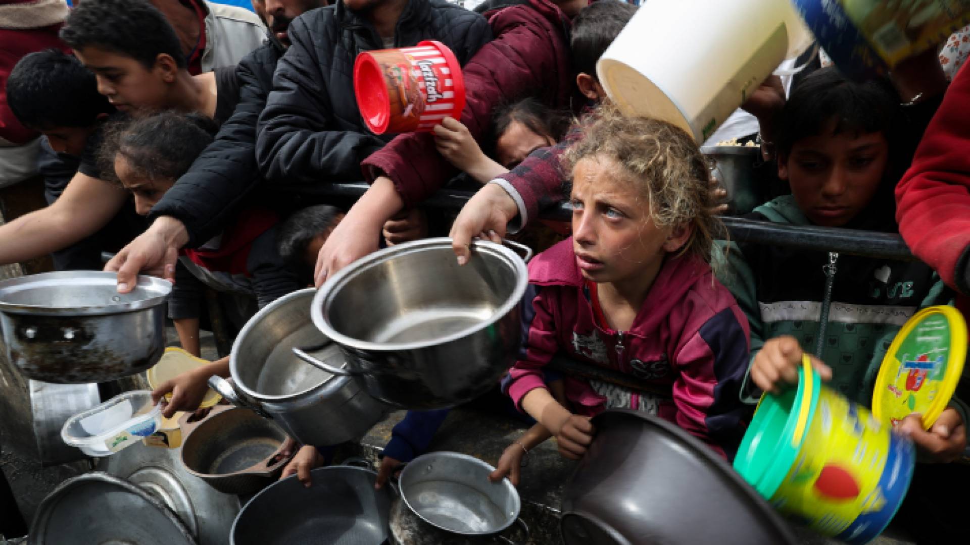 أشخاص يحاولون الحصول على وجبة غذائية في غزة