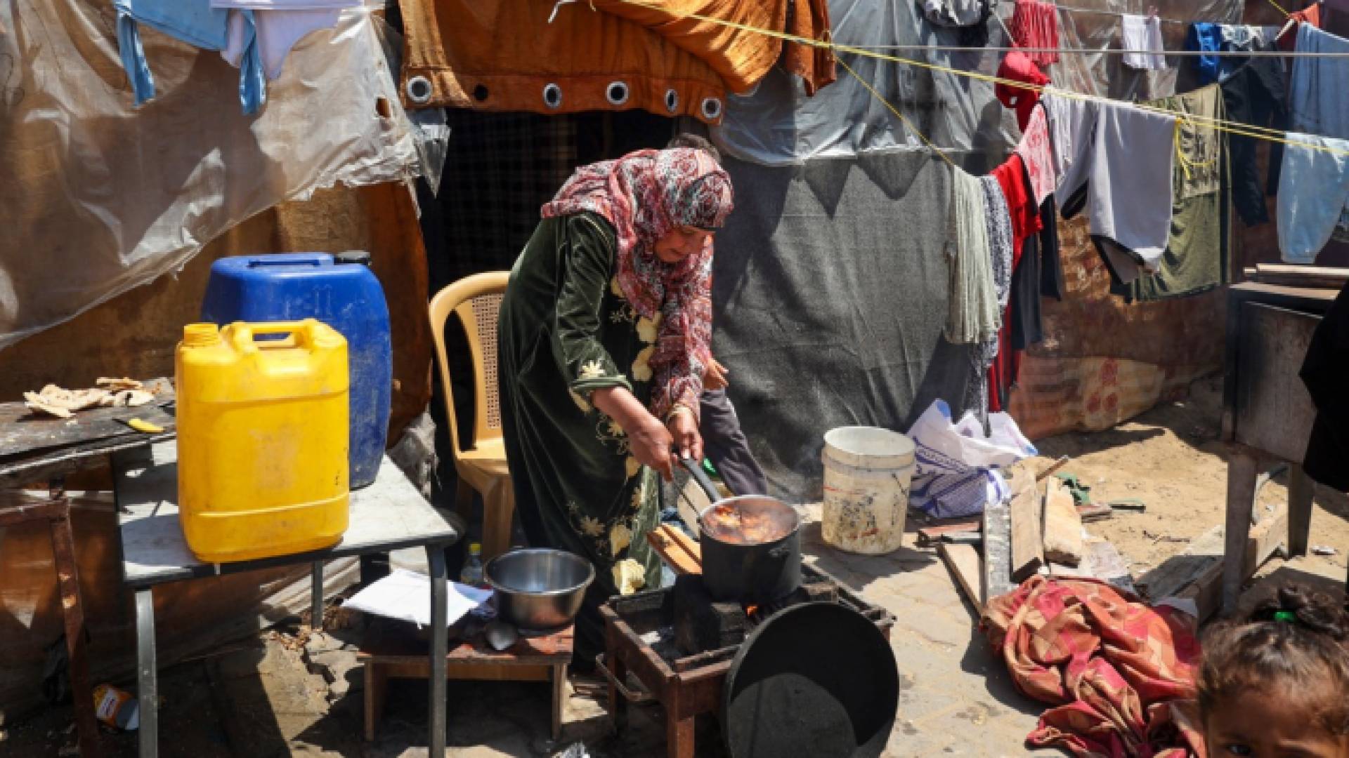 سيدة تطبخ خارج مأوى مؤقت في مخيم للنازحين الفلسطينيين في رفح.