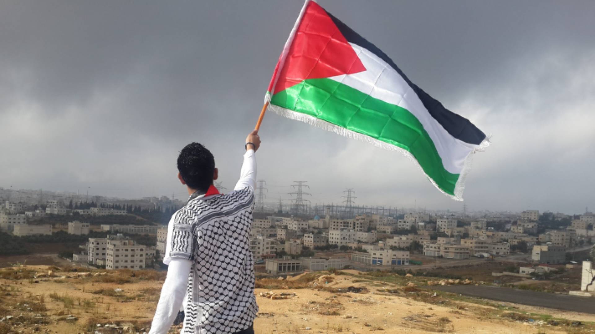 فلسطيني يرفع علم بلاده