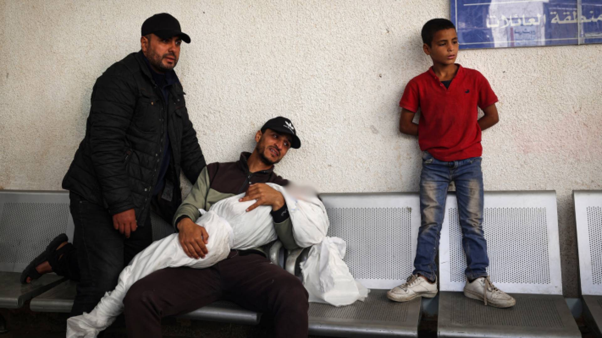 فلسطيني يبكي صغيره في رفح جنوب قطاع غزة