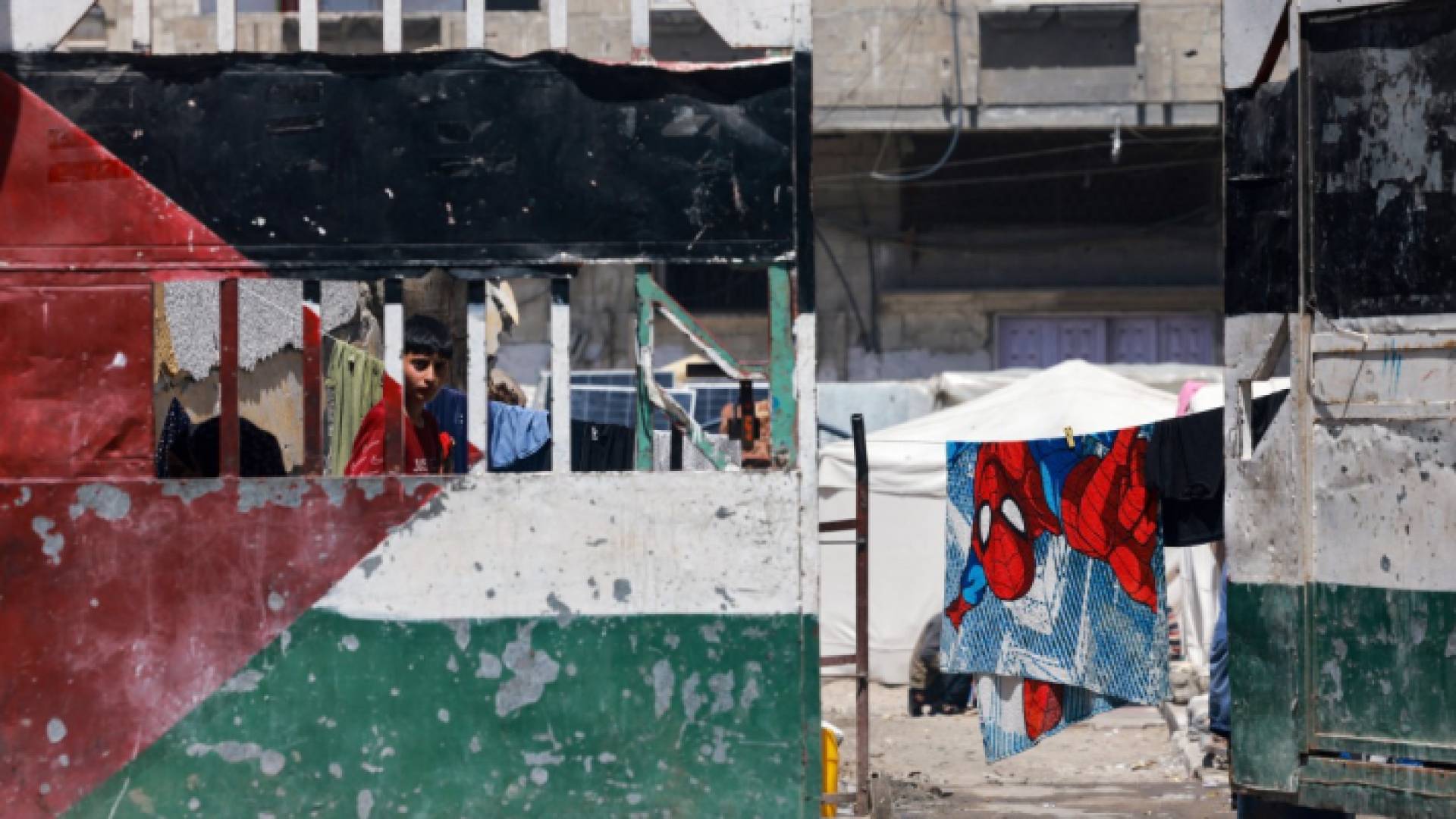طفل ينظر من خلف بوابة في مخيم للنازحين الفلسطينيين في رفح
