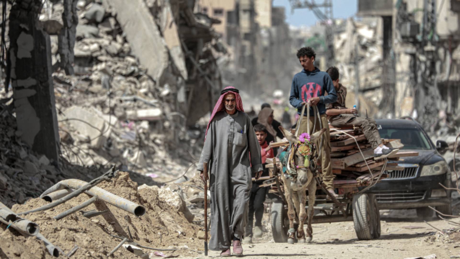 فلسطينيون يسيرون جانب مبان مدمرة في خان يونس بجنوب قطاع غزة - AFP