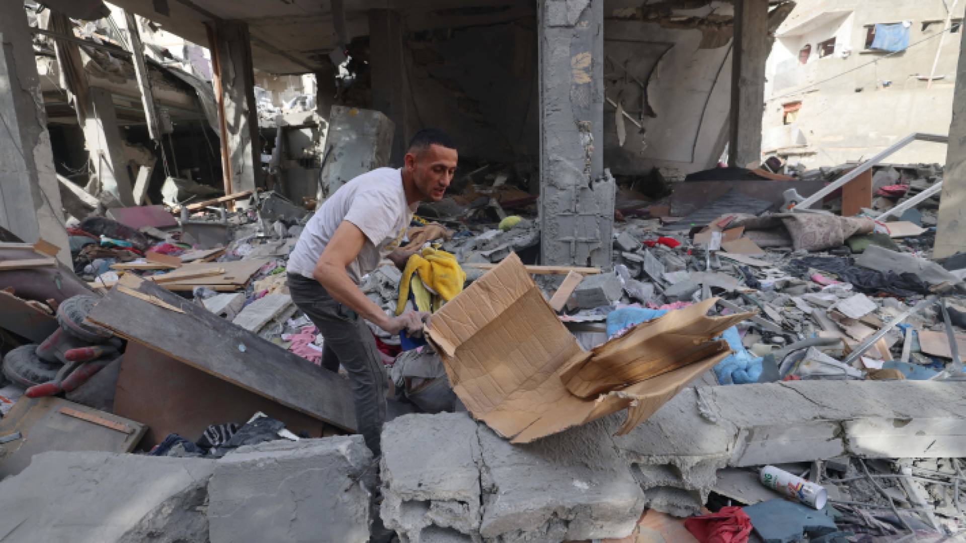 فلسطيني يبحث عن ممتلكات له في أنقاض مبنى مدمر في رفح - AFP